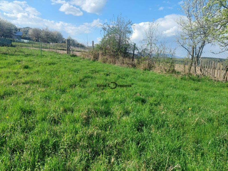 Pozemky pro bydlení ve vesnici Budiná, zelené pastviny a oplocené plochy.