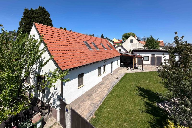 Rodinný dům ve městě Berg s červenou střechou a zeleným trávníkem.