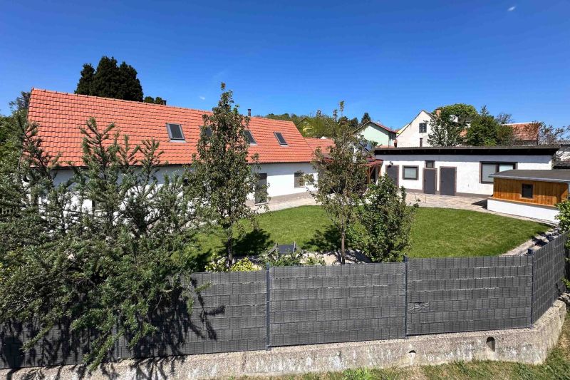 Rodinný dům ve městě Berg se zahradou, plotem a červenou střechou.