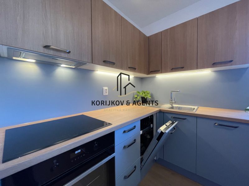 Moderní kuchyně v 2-pokojovém bytě s podlahou s dřevěným dekorem a modrými skříňkami.