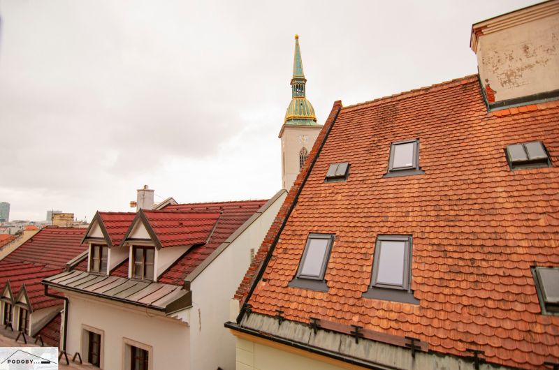 Kostelní věž vyčnívající nad střechami v Bratislavě na Beblavého ulici.