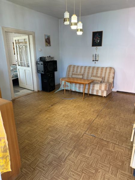 Obývací pokoj v rodinném domě s pohovkou a podlahou s dřevěným dekorem.