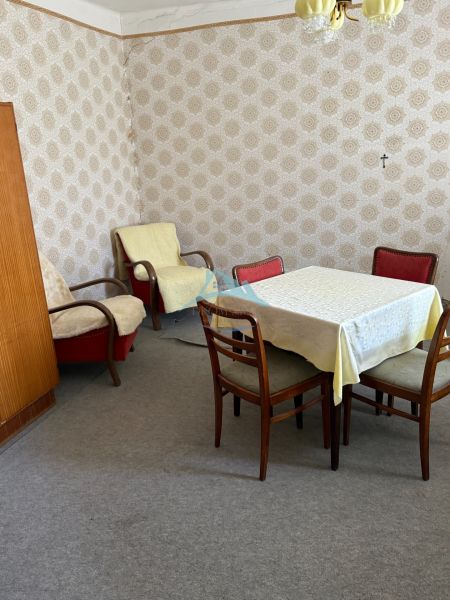 Pokoj v rodinném domě s retro nábytkem, tapetami a kobercovou podlahou.
