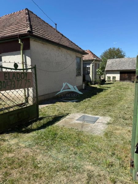 Rodinný dům v Hont má upravený dvůr s trávníkem a přístupem z brány.