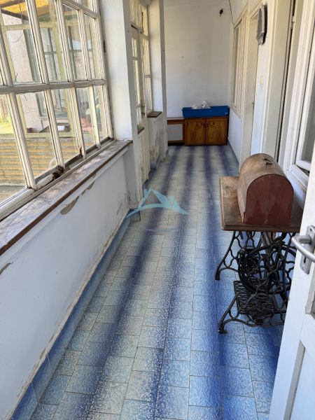 Chodba v rodinném domě s modrými dlaždicemi a velkými okny.