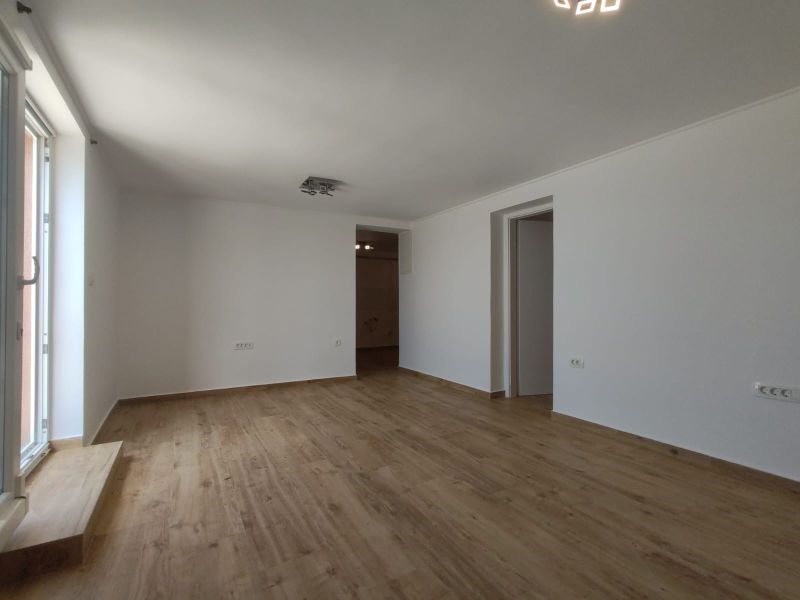 Velká světlá místnost v rodinném domě s podlahou s dřevěným dekorem.