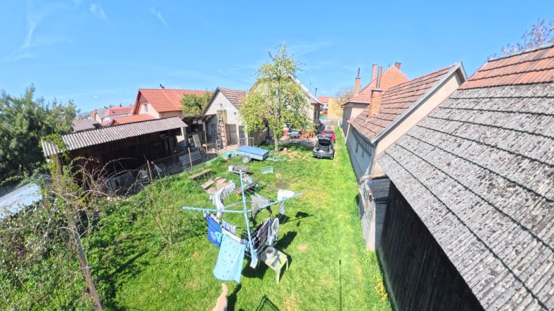 Zahrada rodinného domu v obci Svinná s autem, přístřeškem a sušákem na prádlo.
