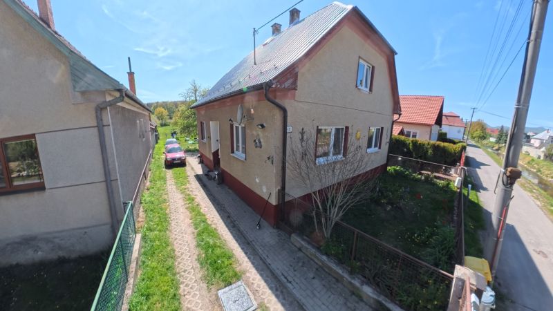 Rodinný dům ve Svinné s automobilem na příjezdové cestě a udržovanou zahradou.