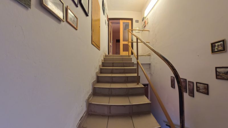 Schodiště s dřevěným zábradlím v rodinném domě, ozdobené obrázky.