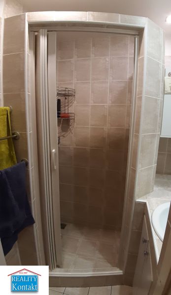 Sprchový kout v koupelně s obkladem v 2-pokojovém bytě.