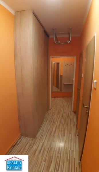 Chodba s oranžovými stěnami a podlahou s dřevěným dekorem v 2-pokojovém bytě.