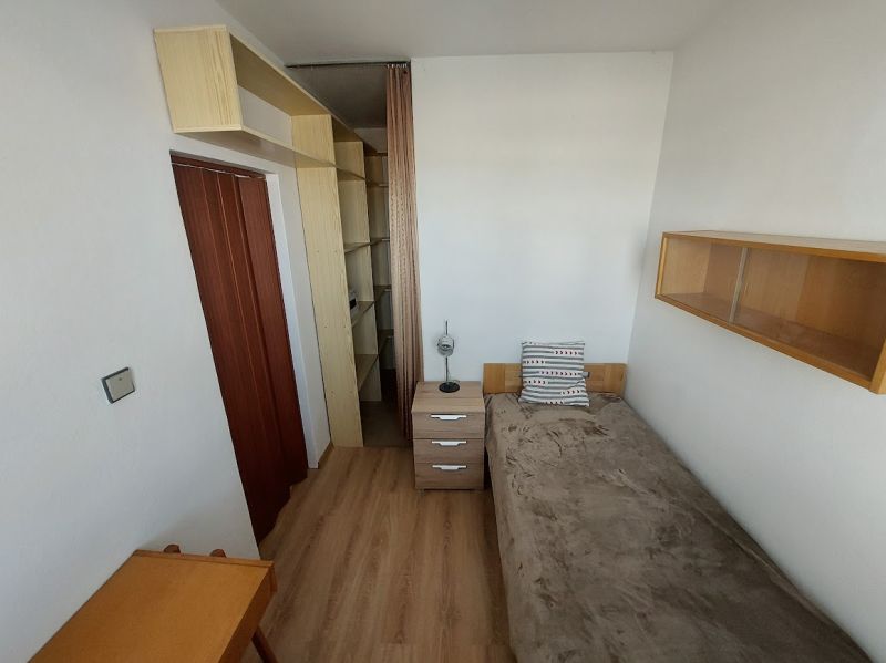 Pokoj v 1-pokojovém bytě s podlahou s dřevěným dekorem, postelí a poličkami.