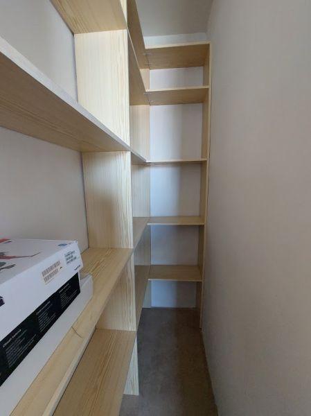 Úzká místnost s policovou sestavou a úložnými prostory v 1-pokojovém bytě.