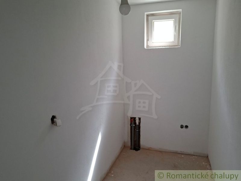 Malý pokoj v rodinném domě s oknem a přípravou na instalace.