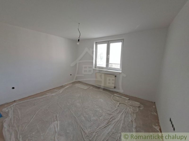 Prázdný pokoj v rodinném domě, bílé stěny, plastový obal na podlaze.