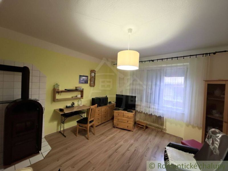 Obývací pokoj s kamny, nábytkem ze dřeva a podlahou s dřevěným dekorem.