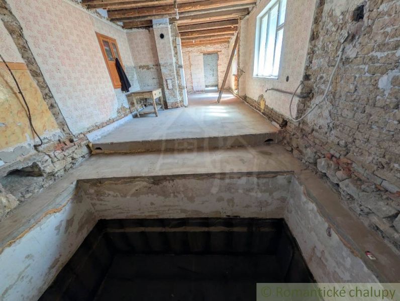 Interiér rodinného domu v rekonstrukci s odkrytými zdmi a schodištěm.