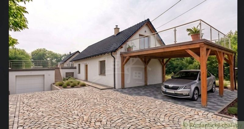 Rodinný dům v Sobotišti se šikmou střechou, terasou a dřevěným přístřeškem pro auto.