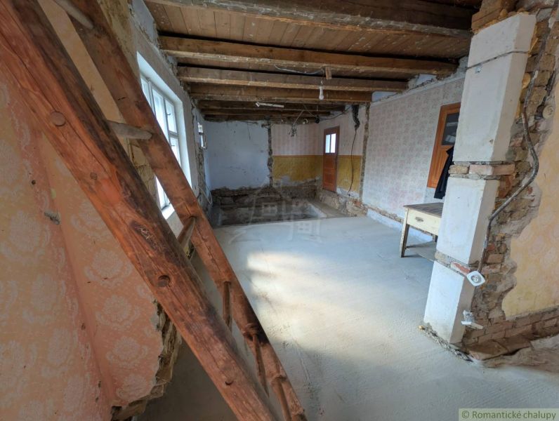 Interiér rodinného domu s dřevěným stropem, starými tapetami a žebříkem.