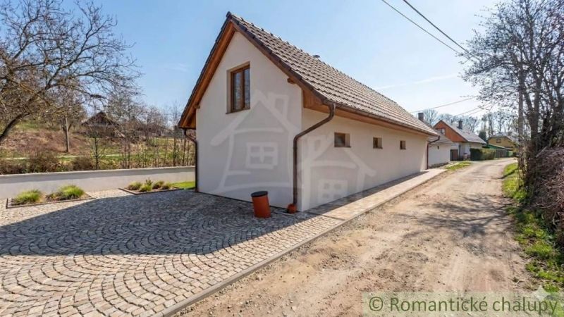 Rodinný dům v Sobotišti s dlážděnou příjezdovou cestou, obklopený zelení a stromy.