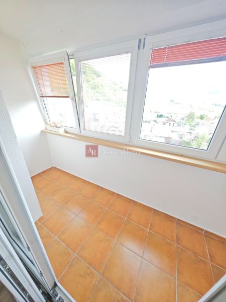 Světlá lodžie se sklem a terakotovou dlažbou v 3-pokojovém bytě.