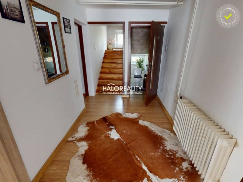 Interiér rodinného domu s podlahou s dřevěným dekorem a schodištěm se zábradlím.