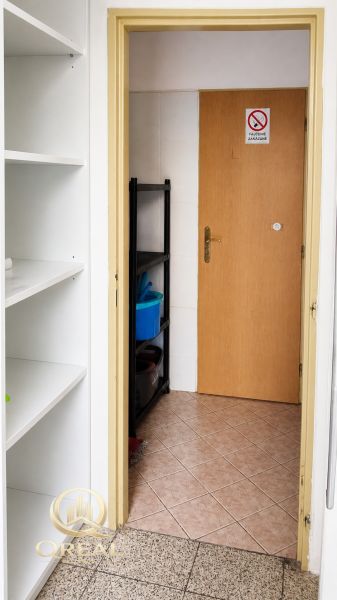 V obchodních prostorách jsou bílé poličky, dveře a regál na čištění.