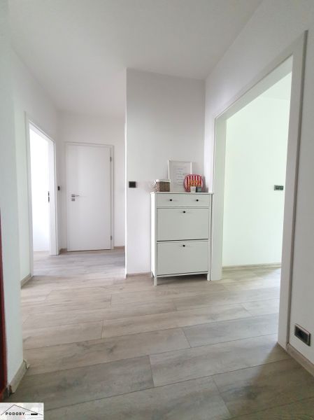 Chodba s bílým nábytkem a podlahou s dřevěným dekorem v 3-pokojovém bytě.