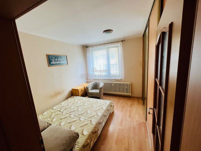 Ložnice s manželskou postelí a podlahou s dřevěným dekorem ve 3pokojovém bytě.