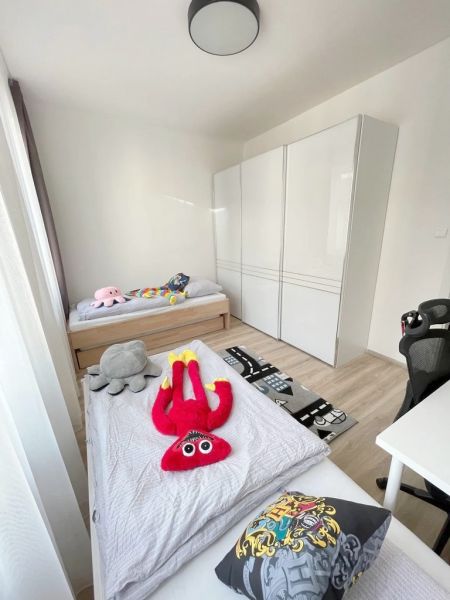 Dětský pokoj ve 3-pokojovém bytě s hračkami a podlahou s dřevěným dekorem.
