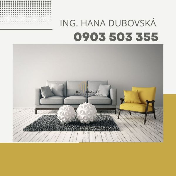 Obývací pokoj s pohovkou a křeslem, dekorativní prvky na dřevěné podlaze.