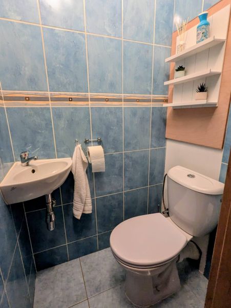 Koupelna s modrými dlaždicemi a toaletou v 2-pokojovém bytě, police na stěně.