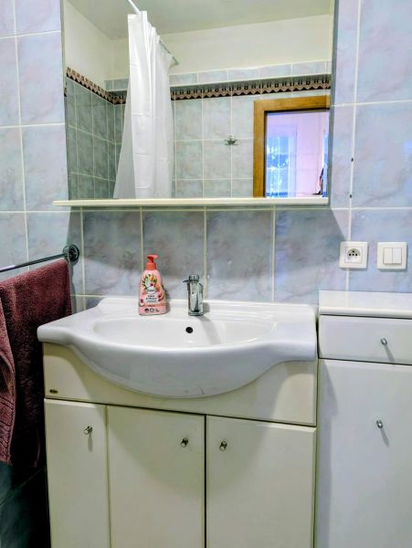 Koupelna v 2-pokojovém bytě s umyvadlem, zrcadlem a modrými obklady.