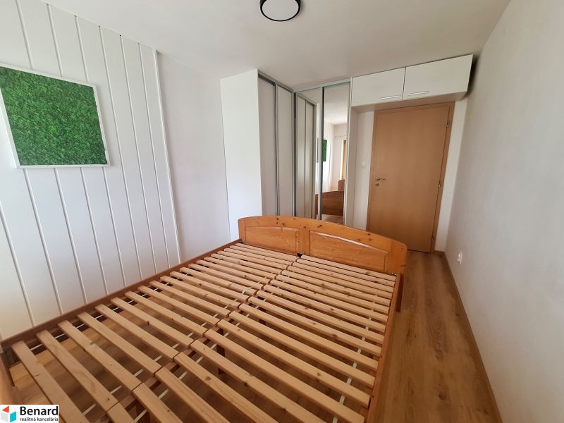 Ložnice v 2-pokojovém bytě s dřevěnou postelí, vestavěnou skříní a dekorací na stěně.