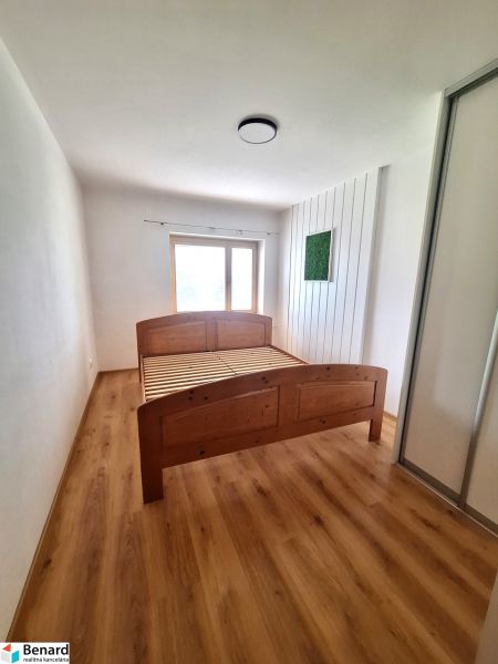 Ložnice s dřevěnou postelí a vestavěnou skříní v 2-pokojovém bytě.