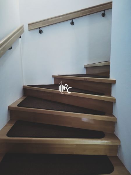 Interiér s dřevěnými schody a zábradlím v rodinném domě.