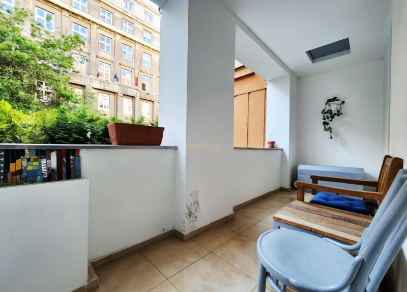 Balkon v 2-pokojovém bytě s květináči a dřevěným nábytkem.