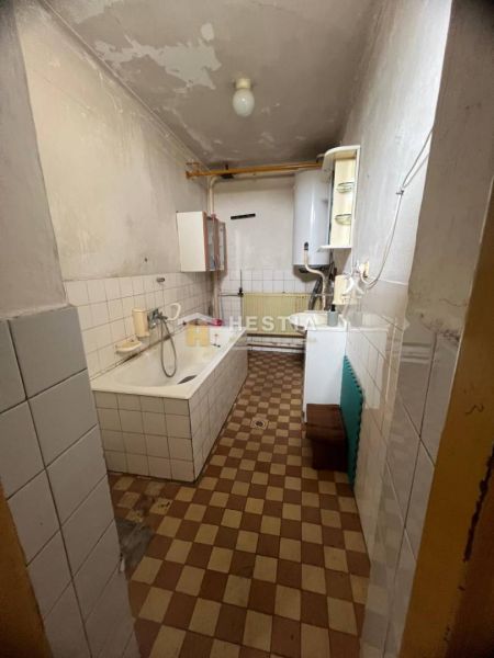 Koupelna s vanou v rodinném domě, obložená kachličkami s radiátorem a plynovým kotlem.