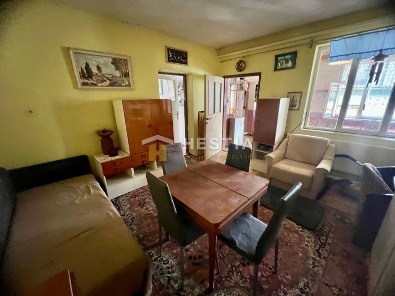 Obývací pokoj rodinného domu s kobercem, dřevěným nábytkem a nástěnnými malbami.