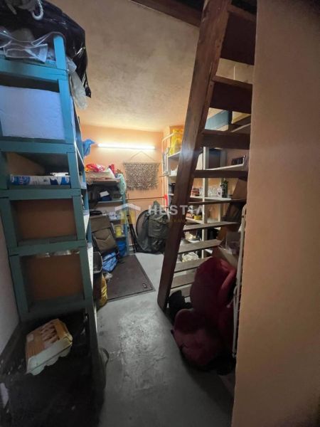 Úložný prostor s policemi a schodištěm v rodinném domě.