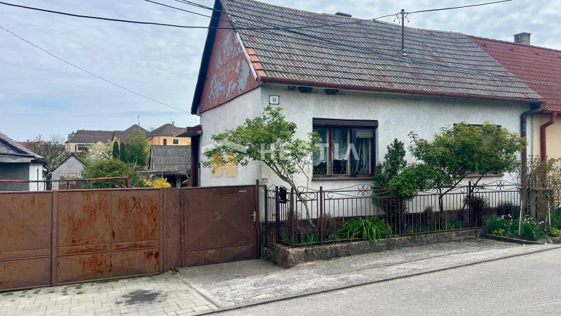 Rodinný dům v Cerové s bránou a malou zahradou, obklopený zelení.