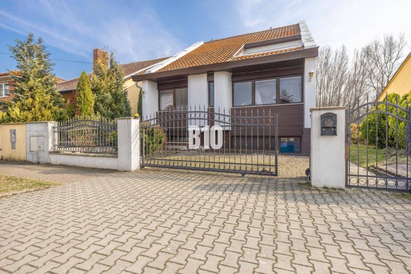Rodinný dům na Dunajské ulici v Hamuliakovu s kovovou bránou a zahradou.
