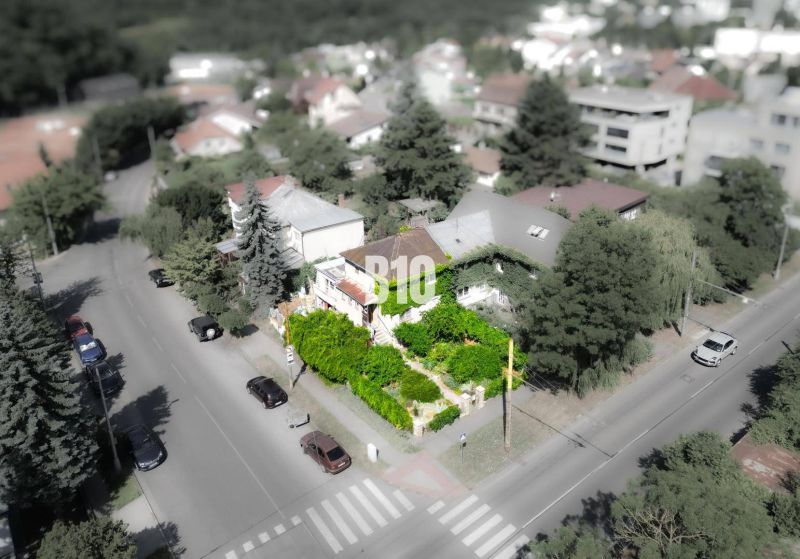 Rodinný dům v lokalitě Bratislava - Staré Město, obklopený zelení a cestou s auty.