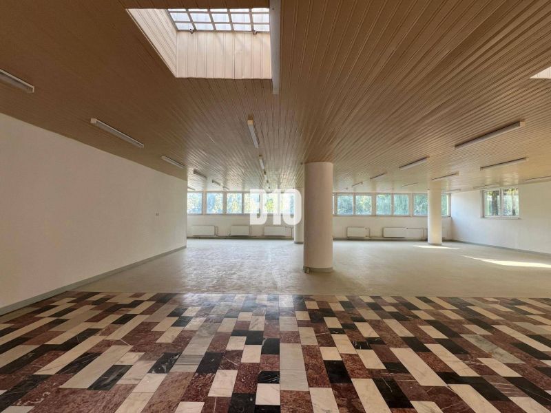 Interiér obchodních prostor s dlažbou a stropními okny nabízí dostatek denního světla.