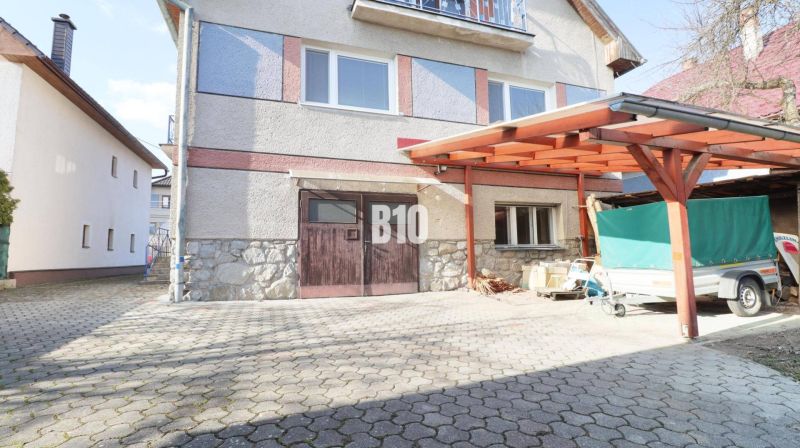 Rodinný dům v Turanech s dřevěným přístřeškem a příjezdovou cestou.