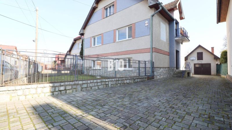Rodinný dům v Turanech s kamenným plotem a dlážděným dvorem.