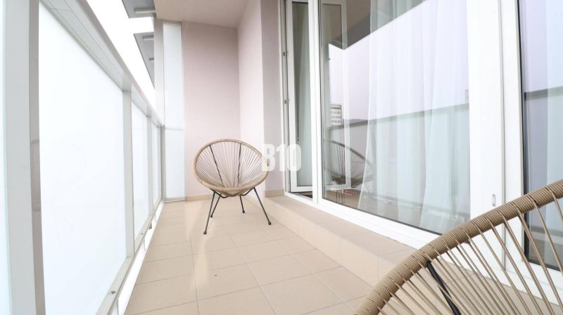 Balkon 1-pokojového bytu se dvěma židlemi a posuvnými dveřmi.