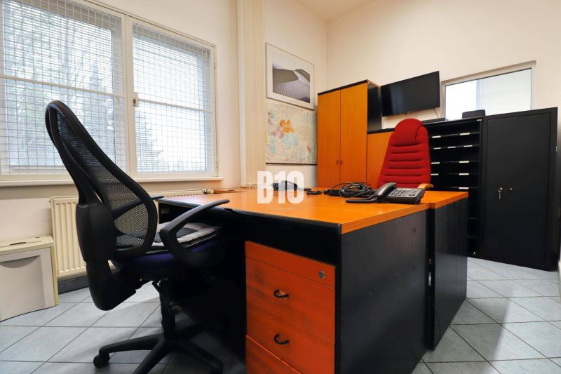 Kancelář ve výrobních prostorách s křesly, stolem a mapou na stěně.