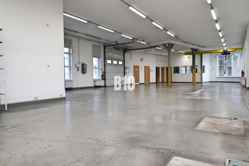 Světlé výrobní prostory s betonovou podlahou a vysokým stropem.