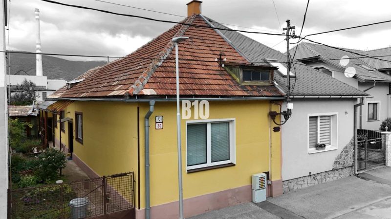 Rodinný dům v Martině se žlutou fasádou a šikmou střechou, vedle přístupového chodníku.